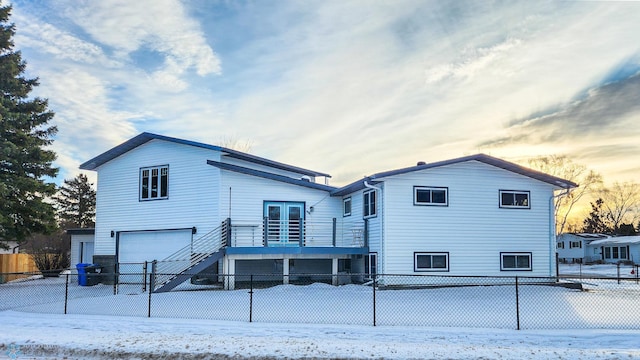 snow covered back of property with a garage