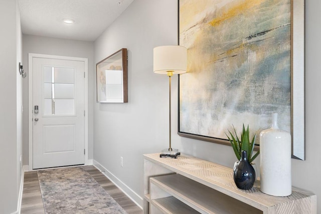 doorway featuring baseboards and wood finished floors