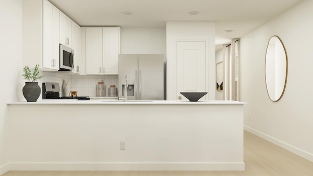 kitchen with backsplash, stainless steel appliances, kitchen peninsula, and white cabinets