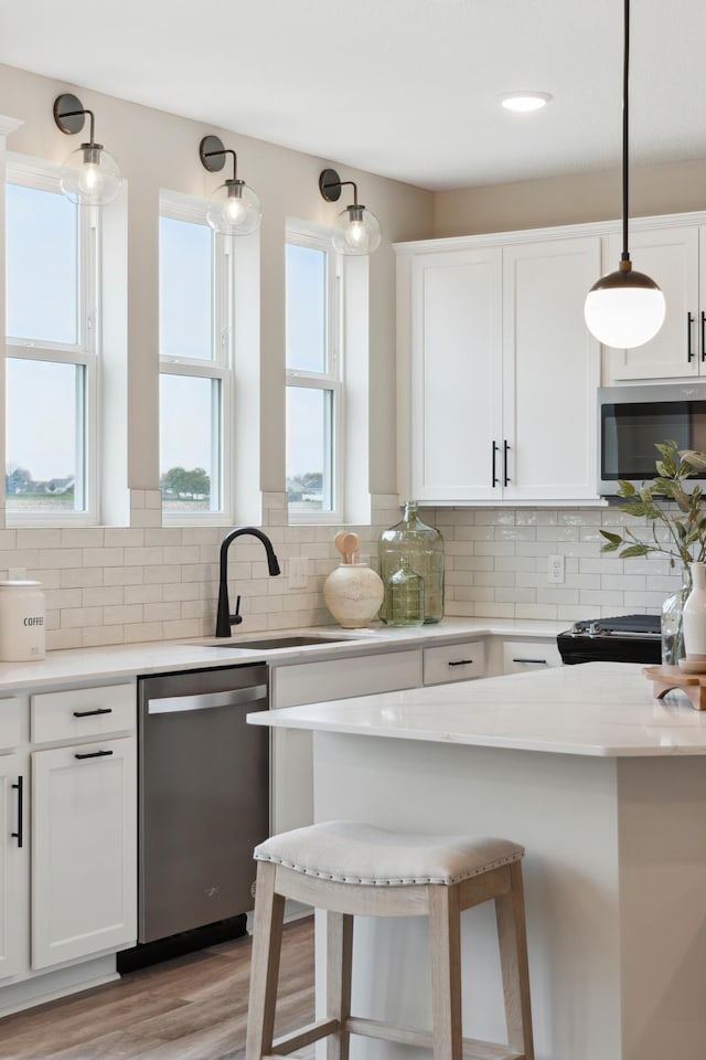 kitchen with decorative light fixtures, stainless steel appliances, decorative backsplash, and white cabinets