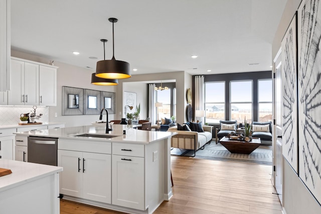 kitchen featuring decorative light fixtures, dishwasher, sink, and white cabinets