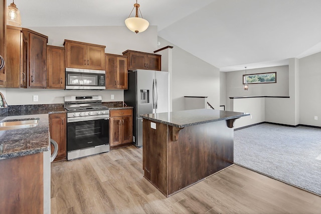 kitchen with sink, a breakfast bar, hanging light fixtures, stainless steel appliances, and vaulted ceiling