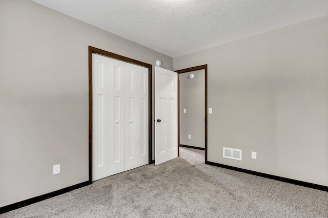 unfurnished bedroom with a closet, light carpet, and a textured ceiling