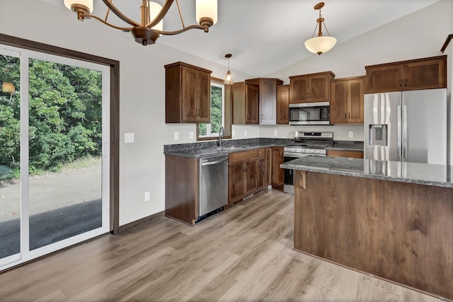 kitchen with sink, dark stone counters, plenty of natural light, pendant lighting, and stainless steel appliances