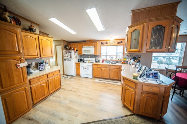 kitchen with lofted ceiling, sink, white appliances, light hardwood / wood-style floors, and backsplash