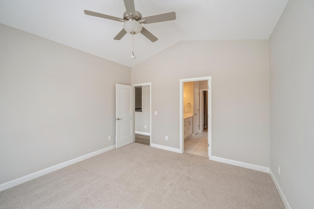 unfurnished bedroom with vaulted ceiling, light carpet, ceiling fan, and ensuite bathroom