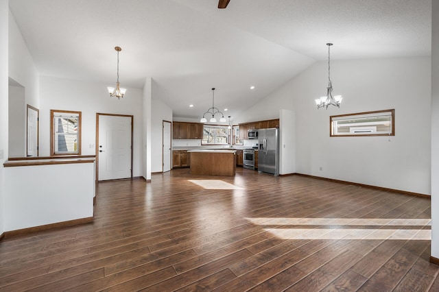 unfurnished living room with high vaulted ceiling, dark hardwood / wood-style floors, and an inviting chandelier