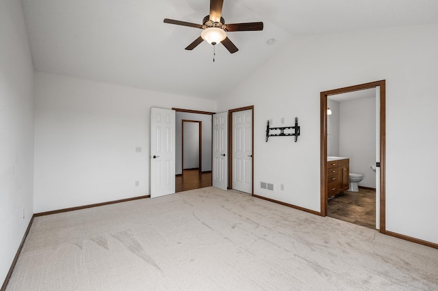 unfurnished bedroom featuring lofted ceiling, connected bathroom, ceiling fan, and carpet