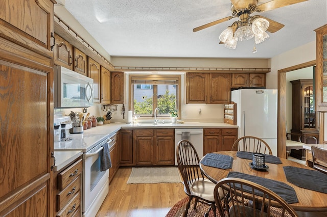 kitchen with sink, white appliances, ceiling fan, a textured ceiling, and light hardwood / wood-style flooring