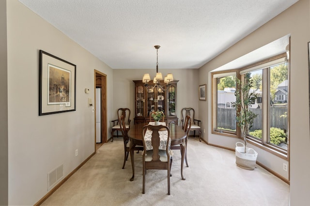 carpeted dining area with a notable chandelier and a textured ceiling