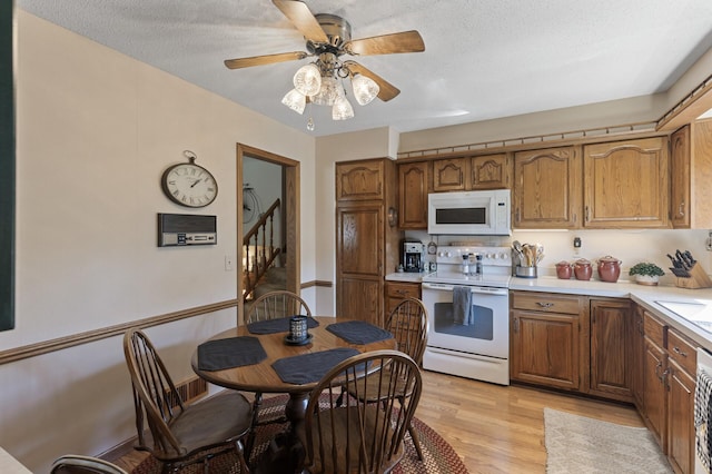 kitchen featuring ceiling fan, white appliances, light hardwood / wood-style flooring, and a textured ceiling