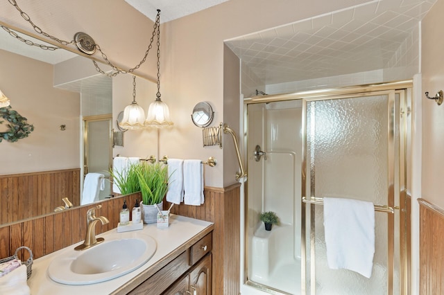 bathroom with vanity, wooden walls, and a shower with door