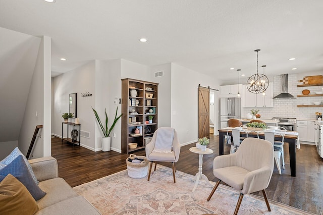 living area featuring a chandelier, a barn door, recessed lighting, baseboards, and dark wood finished floors