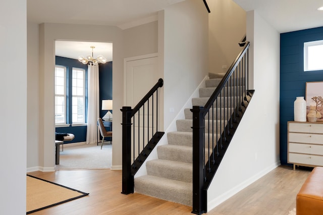 stairs with an inviting chandelier, hardwood / wood-style floors, and plenty of natural light