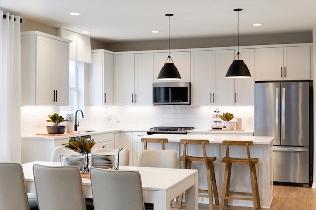 kitchen featuring hanging light fixtures, a center island, white cabinets, and appliances with stainless steel finishes