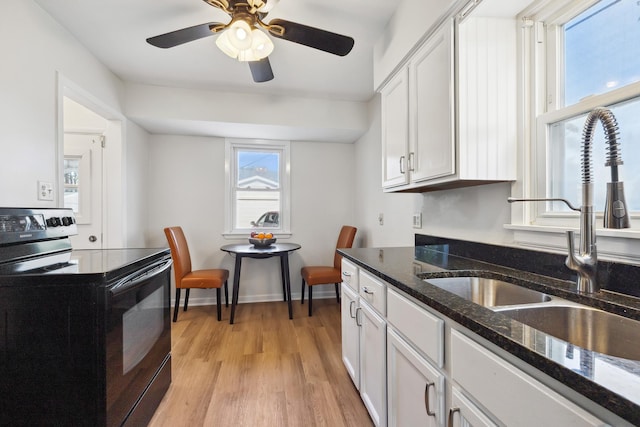 kitchen with white cabinetry, sink, dark stone counters, light hardwood / wood-style floors, and black range with electric stovetop