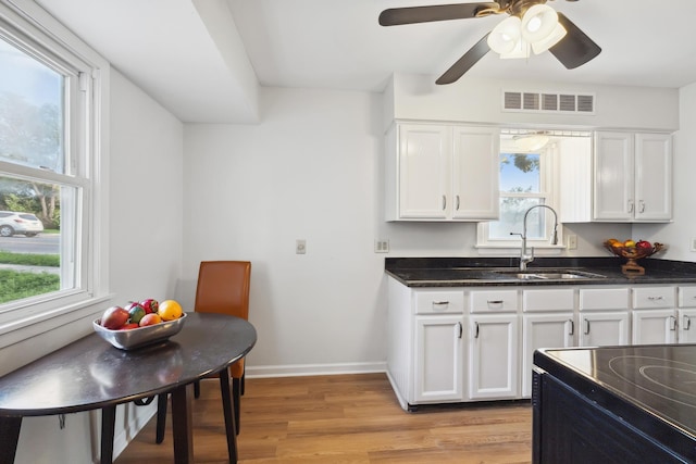 kitchen with light wood-type flooring, electric range, sink, and white cabinets