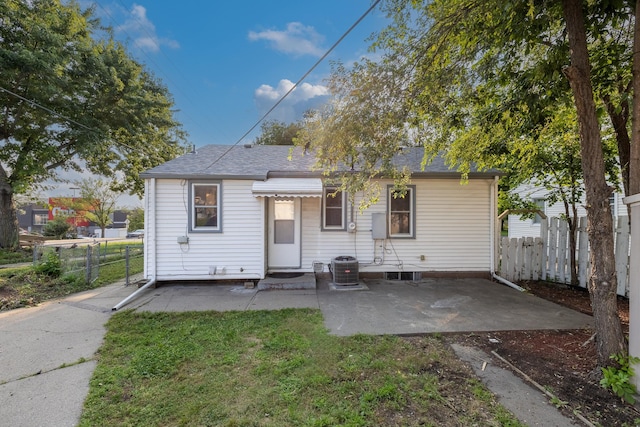 back of house with central AC unit, a patio area, and a lawn