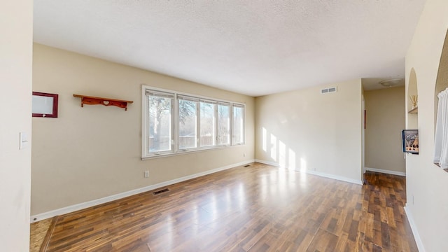 unfurnished room with dark hardwood / wood-style floors and a textured ceiling