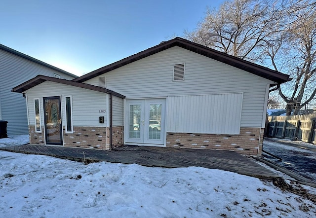 snow covered rear of property with french doors