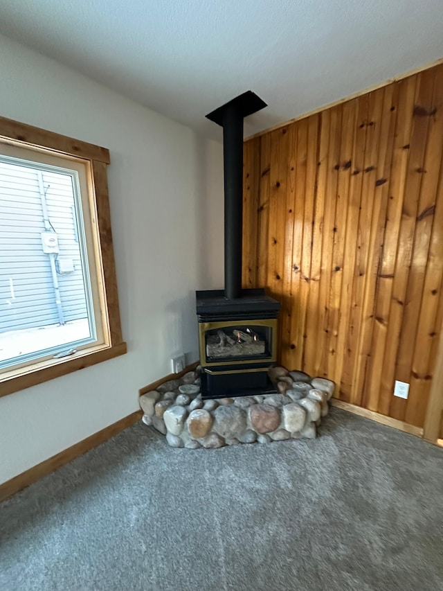 carpeted living room featuring wooden walls and a wood stove