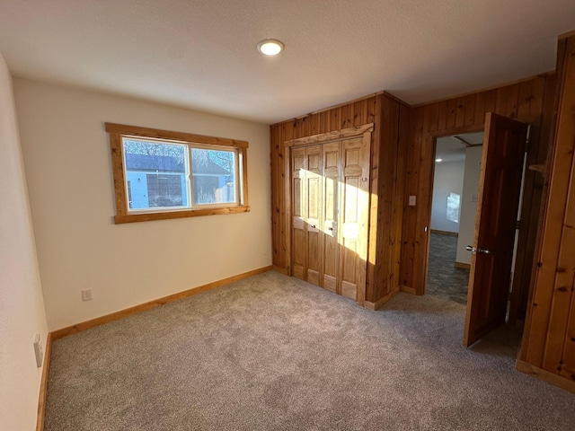 unfurnished bedroom with carpet flooring and wooden walls