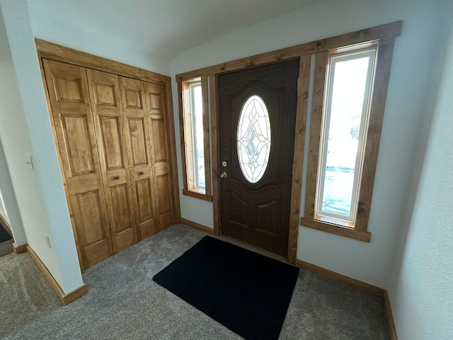 entryway with vaulted ceiling and carpet flooring