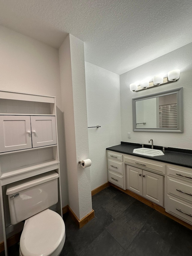 bathroom with a textured ceiling, toilet, and vanity