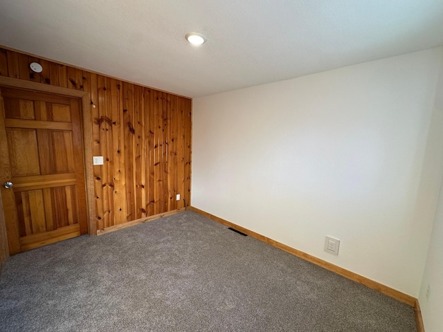 carpeted spare room with wood walls