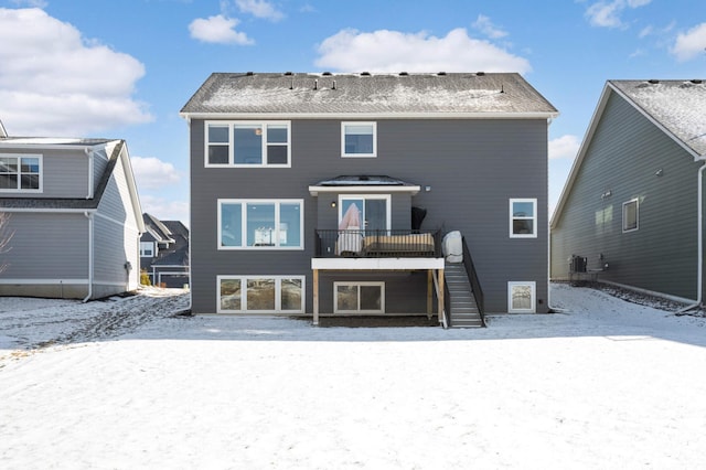 snow covered property with central AC unit and a deck