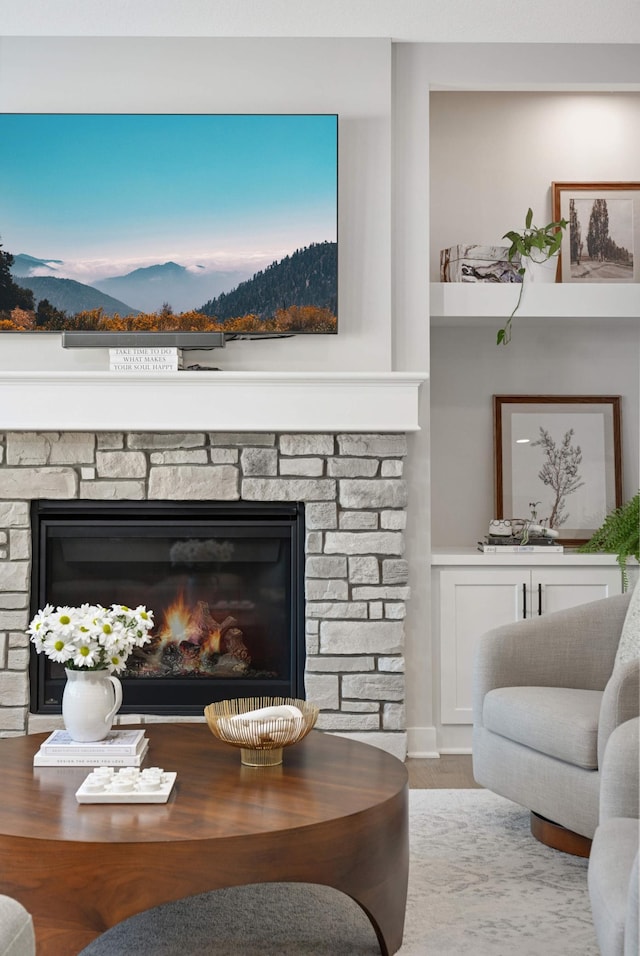 living room featuring a stone fireplace and light hardwood / wood-style flooring