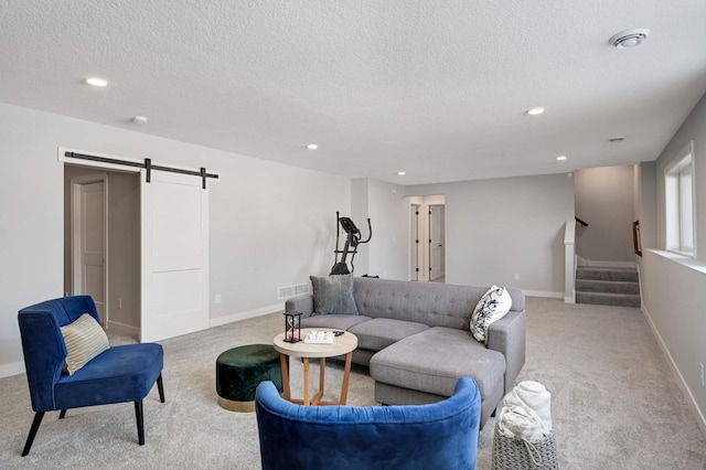 living room with light carpet, a barn door, and a textured ceiling