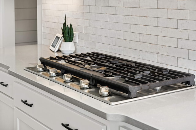 room details featuring white cabinetry, backsplash, and stainless steel gas stovetop