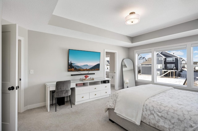 carpeted bedroom with ensuite bath, a raised ceiling, and a textured ceiling