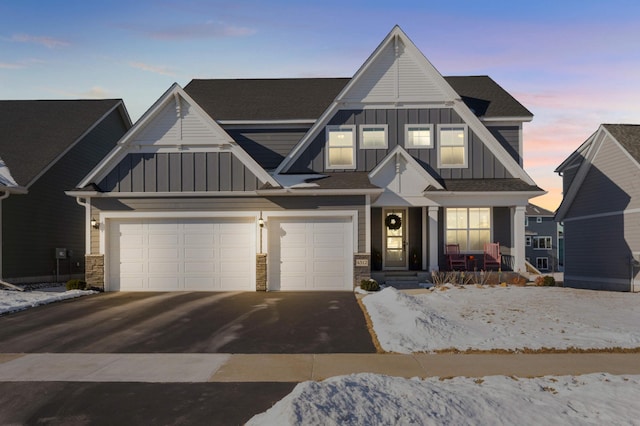 view of front facade with covered porch, driveway, board and batten siding, and stone siding