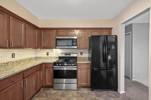 kitchen with light stone counters, stainless steel appliances, and backsplash