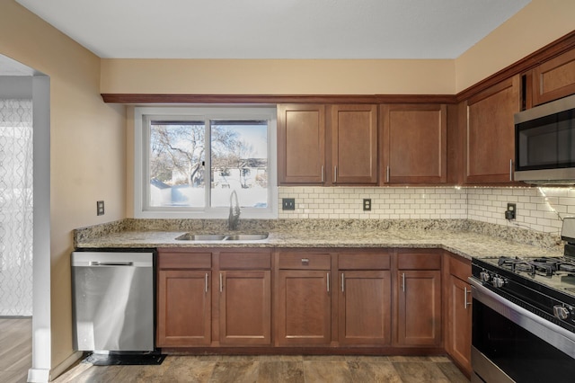 kitchen with tasteful backsplash, appliances with stainless steel finishes, sink, and light stone counters