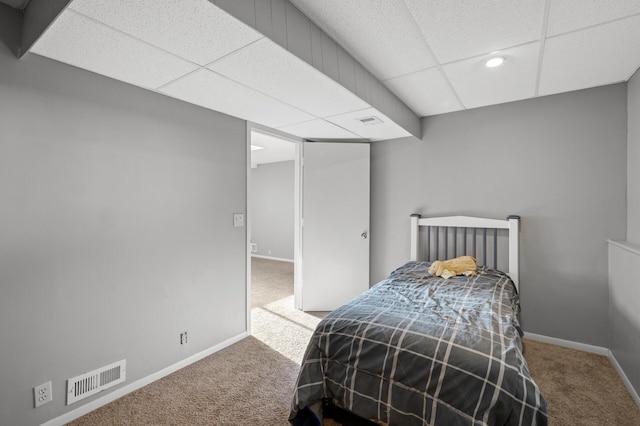 carpeted bedroom featuring a drop ceiling