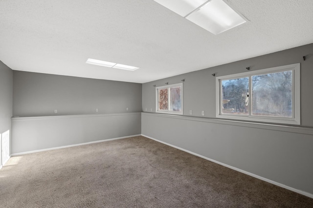 carpeted spare room with a skylight, a wealth of natural light, and a textured ceiling