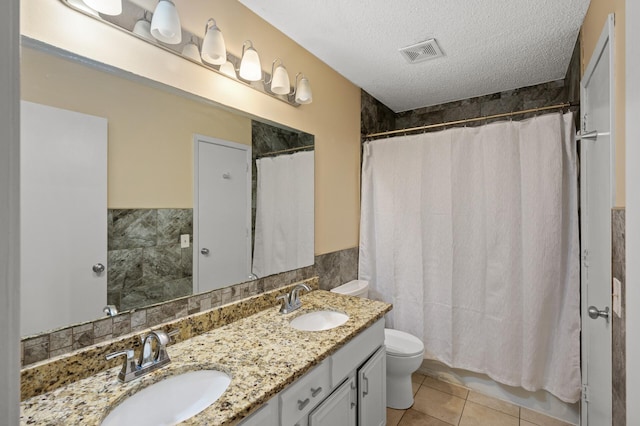 bathroom with vanity, toilet, tile patterned flooring, and a textured ceiling