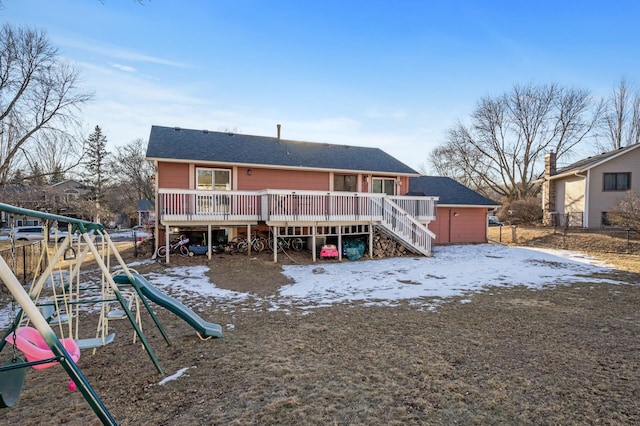 snow covered house featuring a wooden deck and a playground