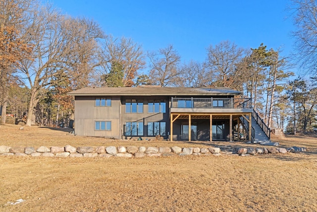 back of property featuring a wooden deck and a lawn