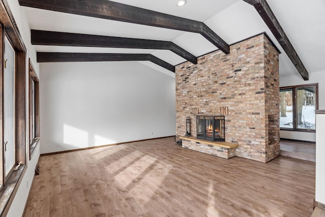 unfurnished living room featuring vaulted ceiling with beams, wood-type flooring, and a brick fireplace