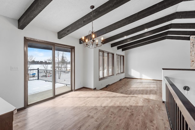 unfurnished dining area featuring lofted ceiling with beams, a textured ceiling, an inviting chandelier, and light hardwood / wood-style flooring