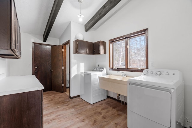 laundry area featuring cabinets, washer and clothes dryer, sink, and light hardwood / wood-style flooring