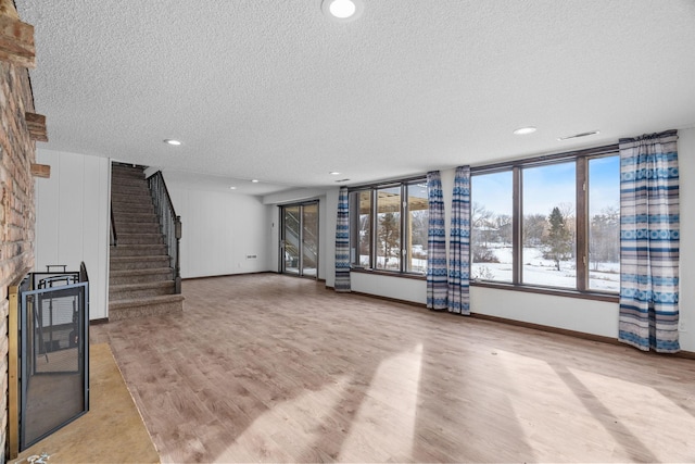 unfurnished living room featuring light hardwood / wood-style flooring, a large fireplace, and a textured ceiling