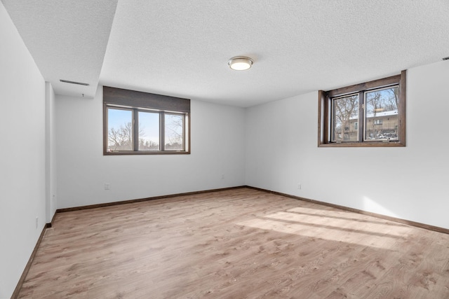 unfurnished room featuring a textured ceiling, a healthy amount of sunlight, and light wood-type flooring