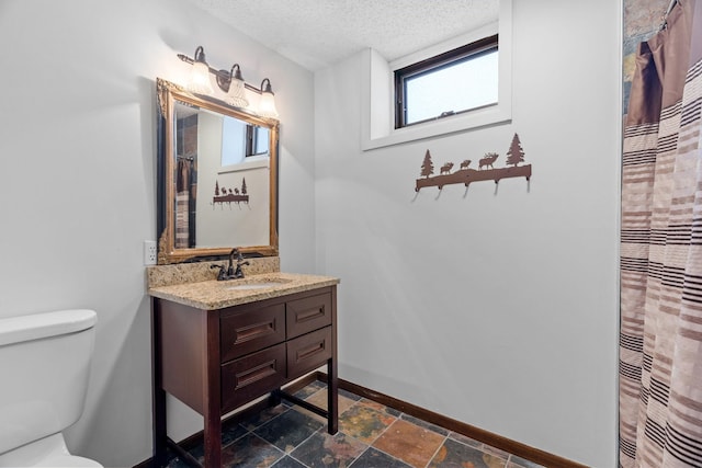 bathroom with vanity, a textured ceiling, and toilet