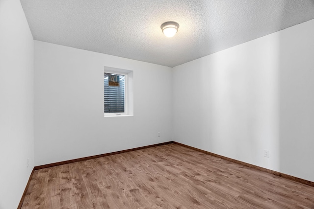 spare room featuring light hardwood / wood-style floors and a textured ceiling