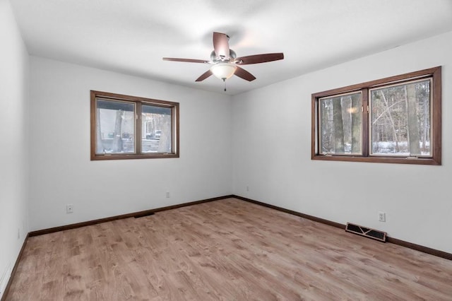 empty room with ceiling fan and light hardwood / wood-style flooring